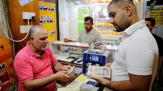 A man counts Iranian rials using a money counting machine at a currency exchange shop in Baghdad, Iraq August 8, 2018. 