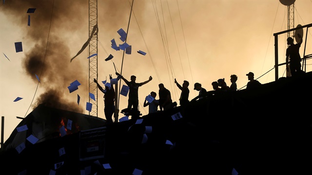 Protesters throw documents as they stand on concrete blast walls during an anti-government protest near the burnt building of the government office in Basra, Iraq September 7, 2018. 