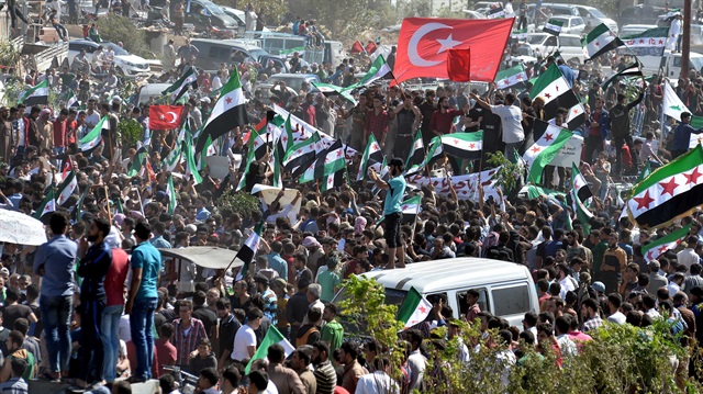 Göstericiler “Biz buradayız, dik duruyoruz, biz özgürüz. Teröristler Şam’da. Devrimi başaracağız” dedi.
