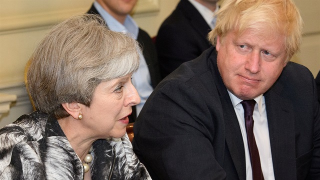 Theresa May sits next to Boris Johnson. 