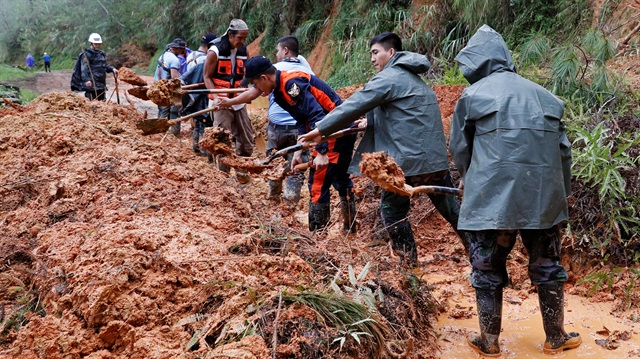 Police officers and fire marshals clear debris and fallen trees caused by a landslide
