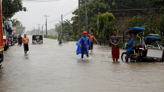 Stranded commuters stand on a partially flooded road after Typhoon Mangkhut 