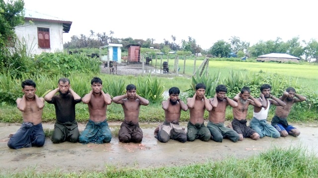Ten Rohingya Muslim men with their hands bound kneel in Inn Din village 