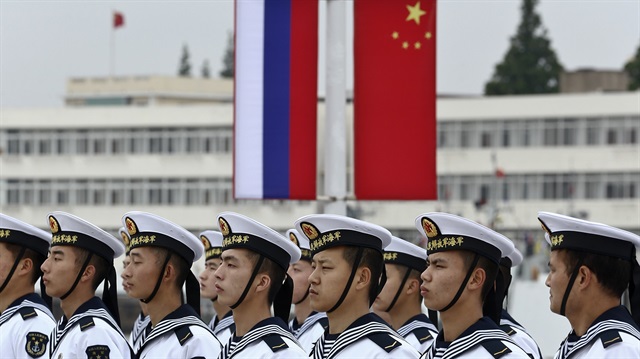 hinese sailors stand in formation in front of national flags of Russia (L) and China