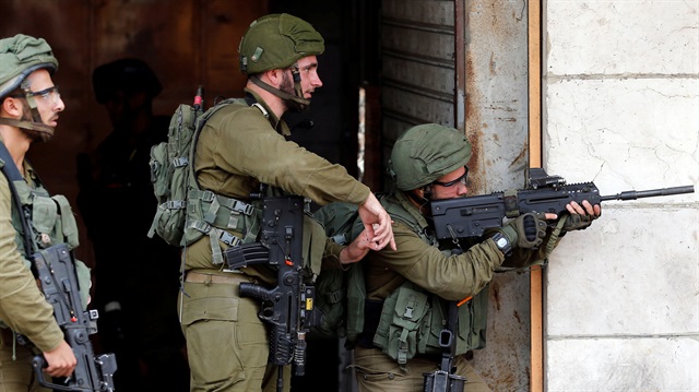 An Israeli soldier aims his weapon 
