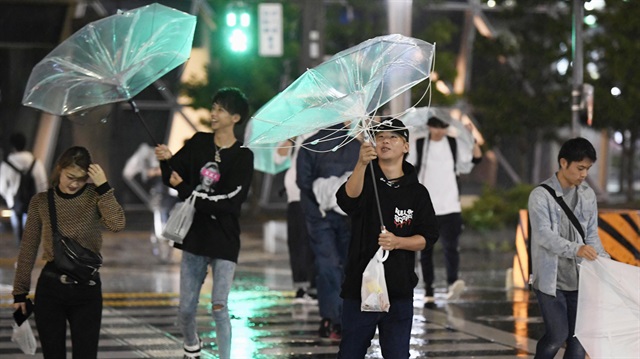 Passersby using umbrellas struggle against strong wind and rain caused by Typhoon Trami 
