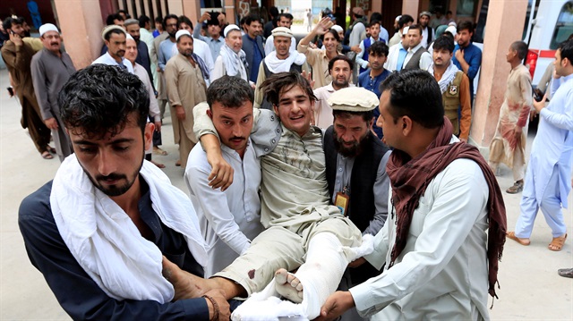 Afghan men carry an injured man to a hospital after a suicide attack, in Jalalabad, Afghanistan 