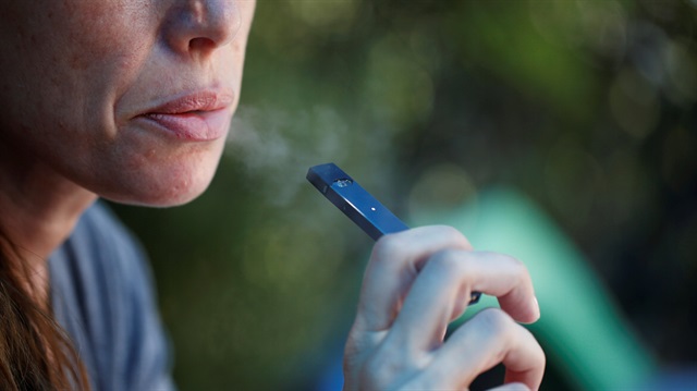 A woman smokes a Juul e-cigarette.