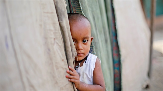 A girl from the Rohingya community stands outside her family's shack in a camp in New Delhi, India