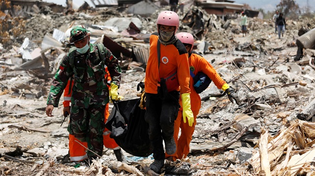 Rescue workers and a soldier remove a victim of last week's earthquake in the Balaroa neighbourhood in Palu, Central Sulawesi, Indonesia October 6, 2018. 