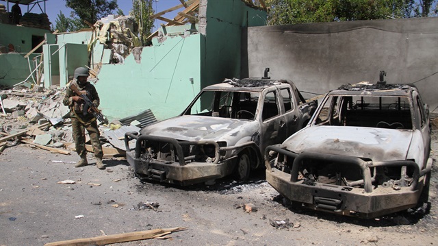 File photo: A member of the Afghan security forces stands guard next to damaged army vehicles after a Taliban attack in Ghazni city