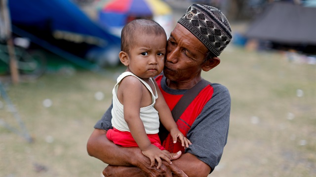 Forjan carries his grandson Rafa outside his tent at a camp for displaced victims of the earthquake and tsunami in Palu, Central Sulawesi, Indonesia, October 9, 2018.