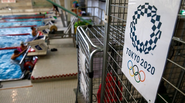 Athletes are pictured beside a sign of the Tokyo 2020 Summer Olympic games during a training session with Syrian refugee 