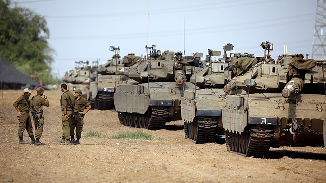 Israeli soldiers speak next to tanks as military armoured vehicles gather in an open area near Israel's border with the Gaza Strip October 18, 2018.