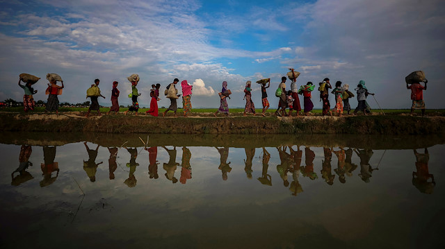 Rohingya refugees are reflected in rain water along an embankment next to paddy fields after fleeing from Myanmar into Palang Khali, near Cox's Bazar, Bangladesh November 2, 2017.