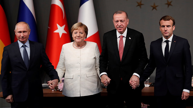 German Chancellor Angela Merkel, Russian President Vladimir Putin, Turkish President Tayyip Erdogan and French President Emmanuel Macron hold hands at a news conference after a Syria summit, in Istanbul, Turkey 
