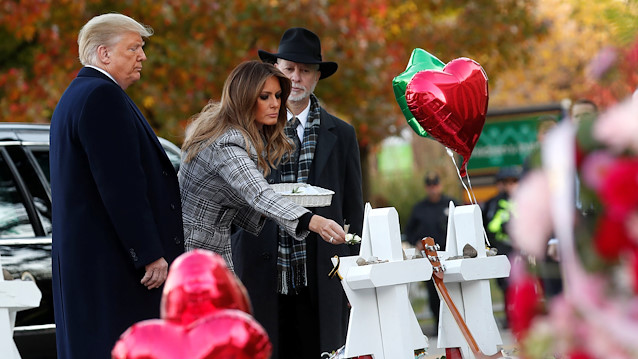 U.S. President Donald Trump watches as first lady Melania Trump places a flower on a memorial to shooting victims as they stand with Tree of Life Synagogue Rabbi Jeffrey Myers outside the synagogue where a gunman killed and wounded people during a mass shooting in Pittsburgh, Pennsylvania, U.S., October 30, 2018. 