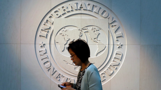 File photo: A woman walks past the International Monetary Fund (IMF) logo at its headquarters