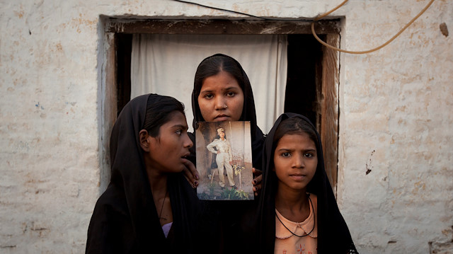 The daughters of Pakistani Christian woman Asia Bibi pose with an image of their mother while standing outside their residence in Sheikhupura located in Pakistan's Punjab Province
