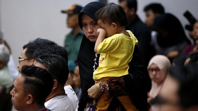 A woman, who had family on the crashed Lion Air flight JT610, walks as she holds her son during a news conference about the recovery process at a hotel in Jakarta, Indonesia, November 5, 2018. 
