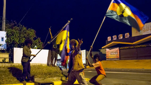 Yeni Kaledonya'da göstericiler, bağımsızlık yanlısı bayrağı tutuyor. 