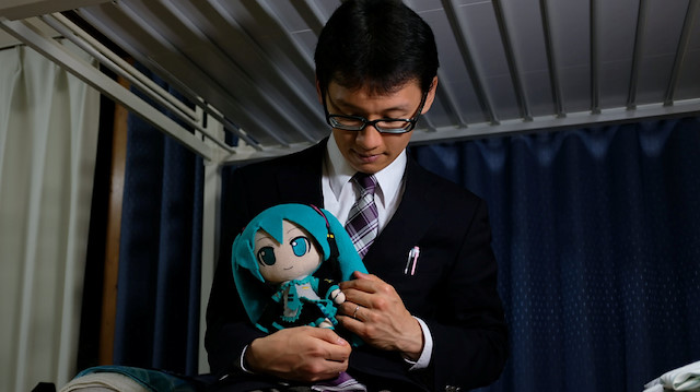 Akihiko Kondo, 35, poses for a photograph with a doll modelled after virtual reality singer Hatsune Miku, wearing their wedding rings, at his apartment after marrying her in Tokyo, Japan November 9, 2018.