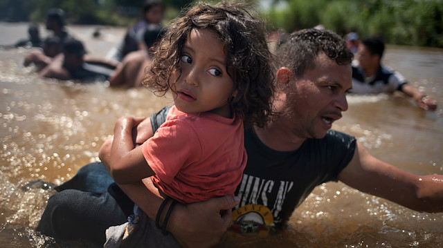 Luis Acosta holds 5-year-old Angel Jesus, both from Honduras, as a caravan of migrants from Central America en route to the United States crossed through the Suchiate River into Mexico from Guatemala in Ciudad Hidalgo, Mexico, October 29, 2018. 