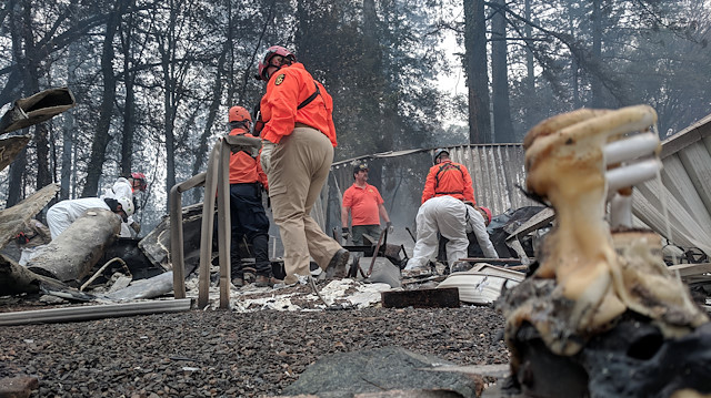Rescue and forensic workers sift through the remains of a burnt-out home destroyed by the Camp Fire in Paradise, California, U.S.