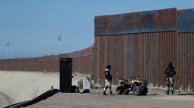 Private security guards stand guard in front of the border fence between Mexico and United States, in Tijuana, Mexico.