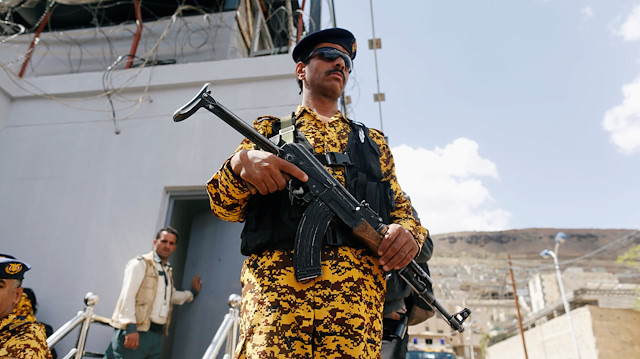A police trooper stands guard as wounded Houthi fighters demonstrate outside the United Nations offices to demand for medical treatment abroad, in Sanaa, Yemen.