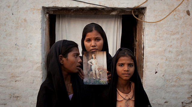 The daughters of Pakistani Christian woman Asia Bibi pose with an image of their mother while standing outside their residence in Sheikhupura located in Pakistan's Punjab Province, November 13, 2010. Standing left to right is Esha, 12, Sidra, 18 and Eshum, 10. 