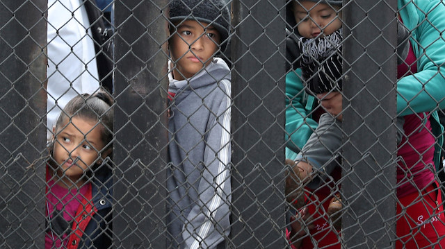 Members of a migrant caravan from Central America and their supporters look through the U.S.-Mexico border wall at Border Field State Park before making an asylum request, in San Diego, California, U.S. April 29, 2018. 
