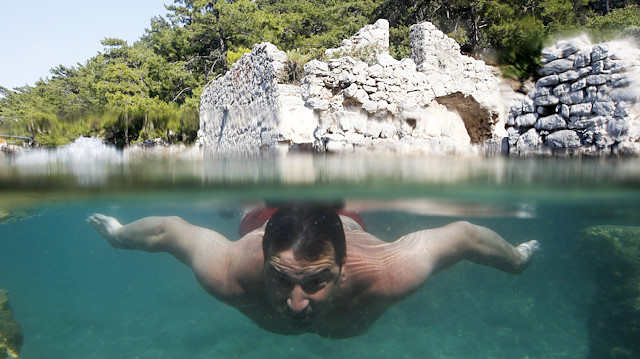 A tourist swims around the flooded ruins of an ancient Roman Bath 