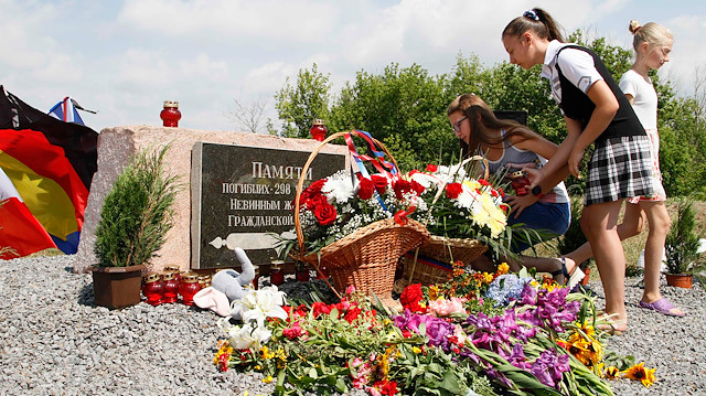 People gather near a monument for the victims of the Malaysia Airlines flight MH17 plane crash 