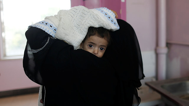 A woman carries a child at the malnutrition ward of al-Sabeen hospital in Sanaa, Yemen 