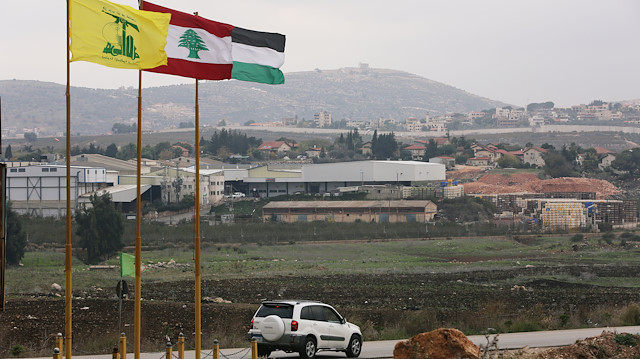 Flags of Hezbollah, Lebanon and Palestine are seen fluttering near the border with Israel 