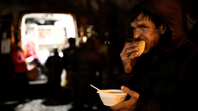 A man eats soup and bread near a van of 'Nochlezhka' charity organization as volunteers distribute meals for homeless people in St. Petersburg, Russia December 5, 2018