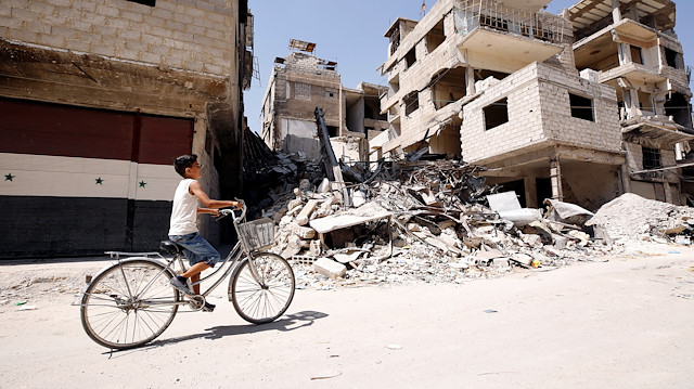 A boy rides on a bicycle along a damaged street in the town of Kafr Batna, in eastern Ghouta, Syria September 5, 2018. 