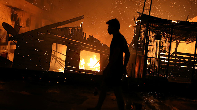 A resident is seen during a fire at Educando neighbourhood, a branch of the Rio Negro, a tributary to the Amazon river, in the city of Manaus, Brazil