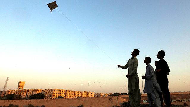 A boy with friends, flies a kite along the dry bed of Lyari River in Karachi