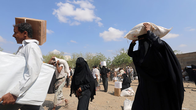 Internally displaced people carry food aid they received, from an ICRC aid distribution centre