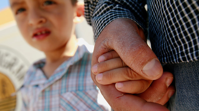 Salvadoran migrant Epigmenio Centeno holds the hand of his three-year old son Steven 