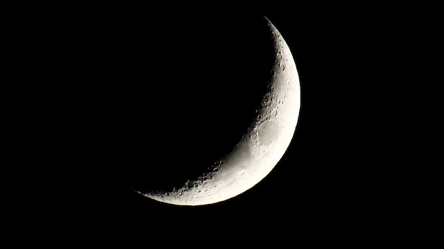 The waxing crescent moon is seen over a city center of Warsaw.