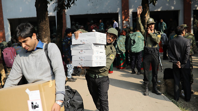 Law enforcement officials carry electronic voting materials as they distribute them to different voting centre ahead of 11th general election which will be held on December 30 in Dhaka, Bangladesh.