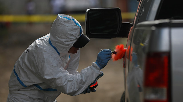 A forensic worker dusts a pick-up truck door for fingerprints after the killing of a man in San Pedro Sula, Honduras.