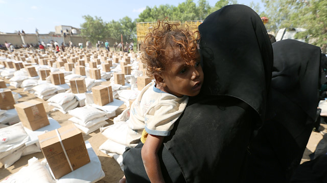 File photo: A woman carries her son as she waits for food aid at an ICRC aid distribution centre in Bajil