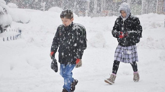 Kar yağışı altında okula giden öğrenciler