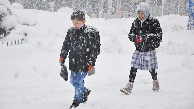 Kar yağışı altında okula gitmeye çalışan öğrenciler.