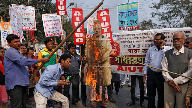 Activists from the All India United Trade Union Centre burn a cut-out depicting India's Prime Minister