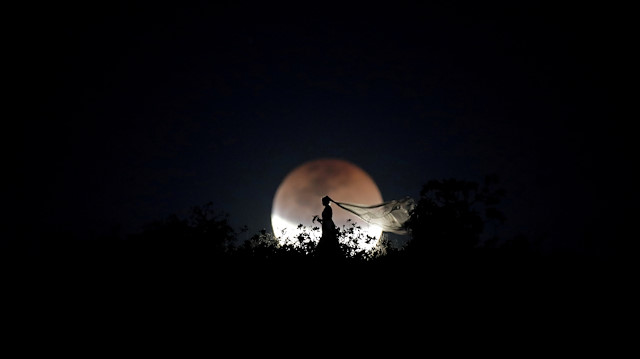 A bride poses for photo during a total lunar eclipse from in Brasilia, Brazil, July 27, 2018. 